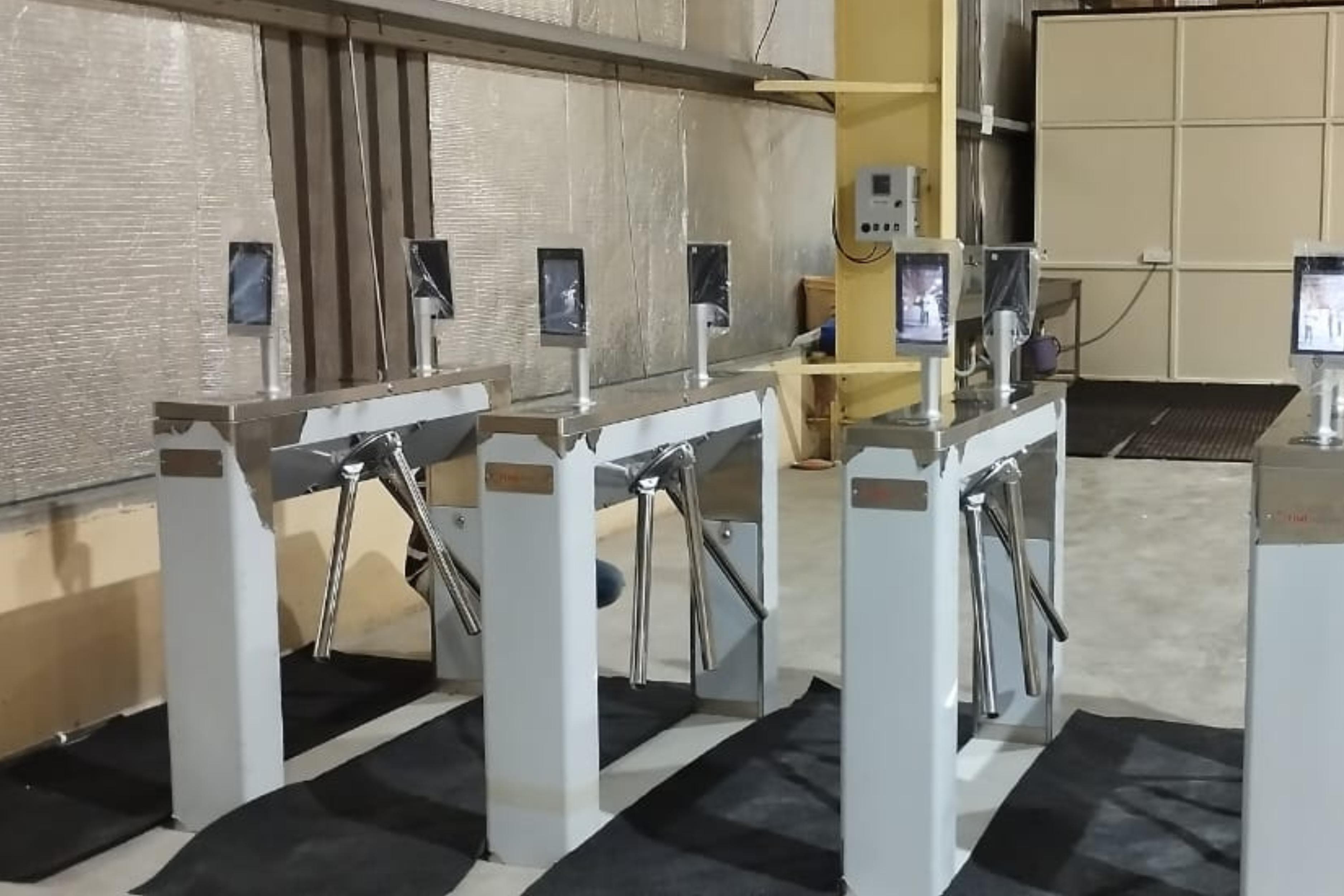 Row of tripod turnstiles with face recognition terminals at an industrial site entrance
